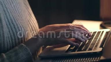 在黑暗的房间里用笔记本电脑工作的女人的手。 快关门。